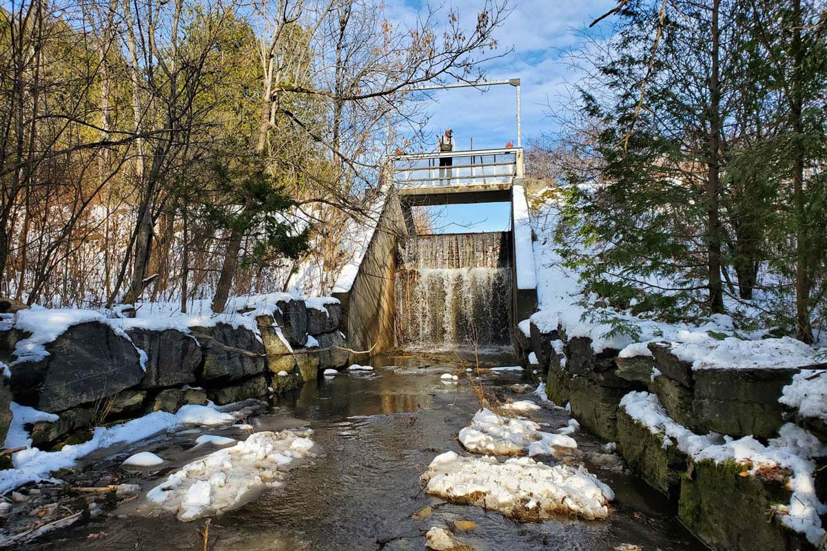 Staff-Balls-Mill-Spillway-Winter GRCA Staff member standing on top of the Ball's Mill spillway
