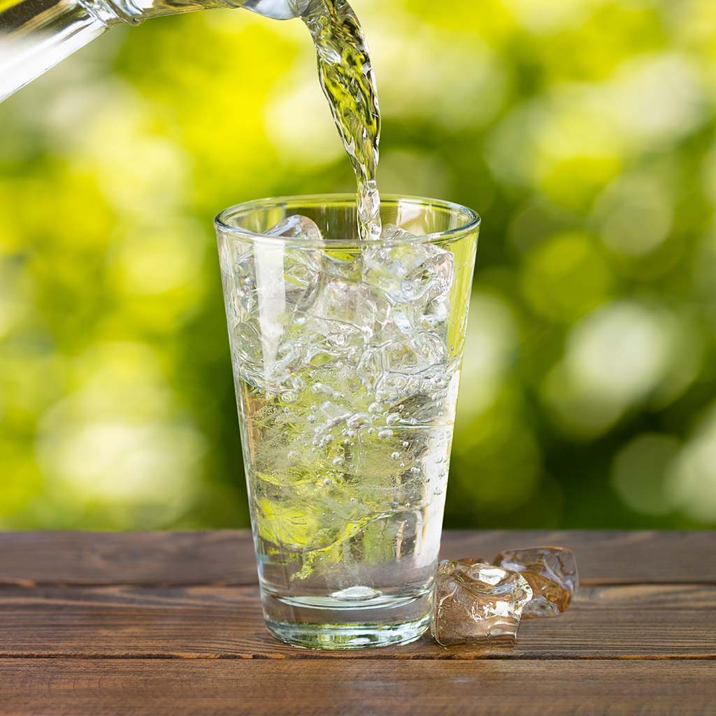 Drinking Water Being Poured Into a Glass With Ice