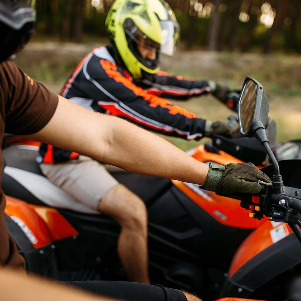 Father and son wearing motorcycle helmets site on 4-wheeled ATVs in the Forest
