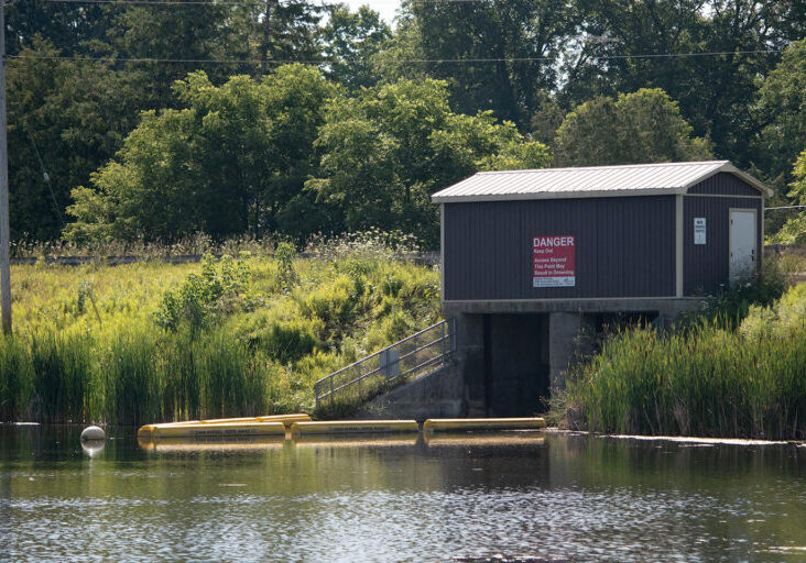 Garden Hill Dam control structure with safety booms in place in the water
