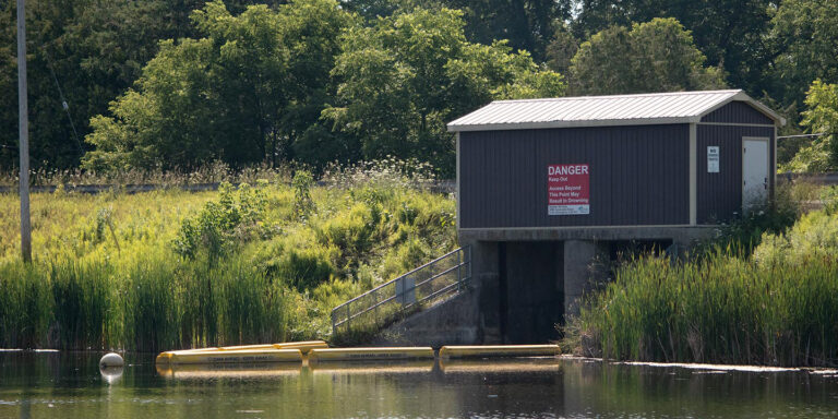 Garden Hill Dam control structure with safety booms in place in the water