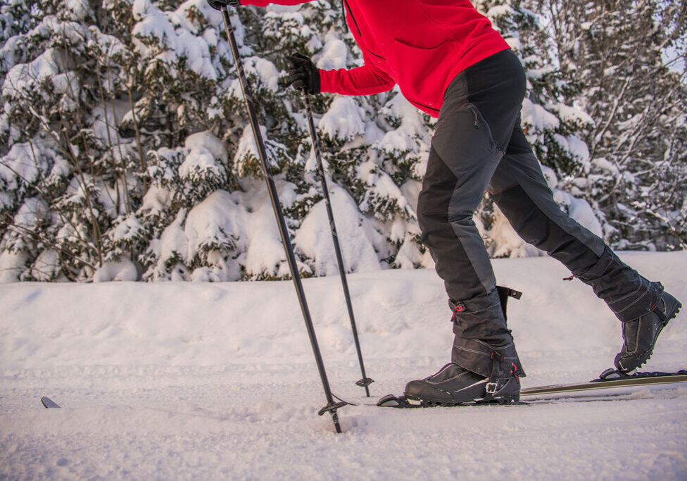 Man in red jacket cross-country skiing on a groomed and trackset trail